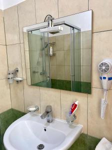 ein Waschbecken mit einem Spiegel und einer Dusche in der Unterkunft Panoramic Apartment Amelia in Sarandë