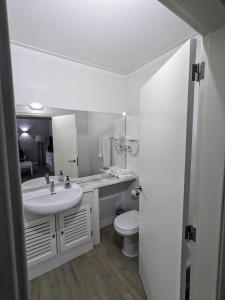 uma casa de banho branca com um lavatório e um WC em VilaBplaza by JohnVillas em Alvor