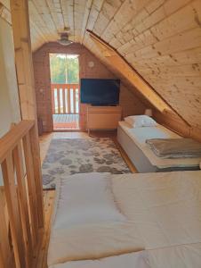 um quarto no sótão com 2 camas e uma televisão em Viherpeukalo lomamökki em Parkano