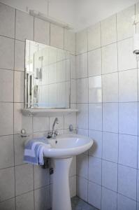 Baño blanco con lavabo y espejo en Costa-Rini Hotel, en Leonidio