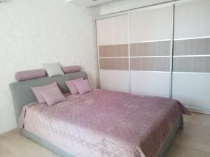 a bedroom with a bed with pink pillows at Apartament Panoramic ALBA IULIA in Chişinău