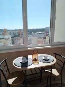 a table and chairs in a room with windows at Apartament Panoramic ALBA IULIA in Chişinău