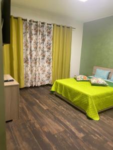 1 dormitorio con cama con colcha verde y cortinas amarillas en Casa Vacanza Mangiafico, en Solarino