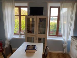 - une salle à manger avec une table et deux fenêtres dans l'établissement Cascina Vica Biella, à Andorno Micca