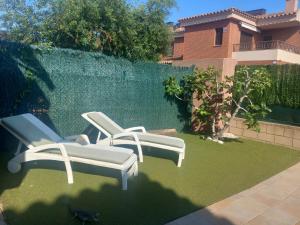 twee ligstoelen op een gazon voor een hek bij Chalet El Dorado Playa in Cambrils