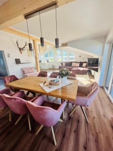 a dining room with a wooden table and pink chairs at Ferienwohnung Lory mit Schlossblick in Halblech