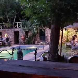 a swimming pool with two benches and a tree at Riad Des Vieilles Charrues in Boumalne