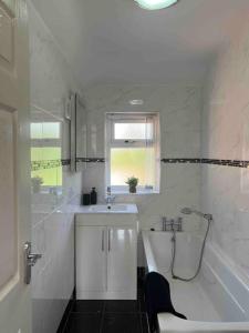ein weißes Badezimmer mit einer Badewanne, einem Waschbecken und einer Badewanne in der Unterkunft Large House/Contractors/Families in Birmingham