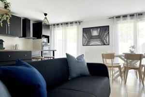sala de estar con sofá negro y cocina en Maison avec jardin proche de Paris, en Mormant