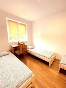 Zimmer mit 2 Betten, einem Schreibtisch und einem Fenster in der Unterkunft Hostel Warszawa Ursynów in Warschau