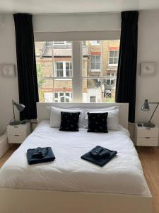 um quarto com uma cama branca com duas toalhas em Luxury Apartment in Belsize Park em Londres