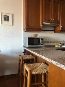 a kitchen with a counter with stools and a microwave at Apartamento en las salinas de Cabo de Gata in El Pozo del Cabo