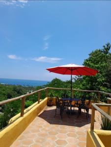 a patio with a table and a red umbrella at Hotel Quinto Sol in Mazunte
