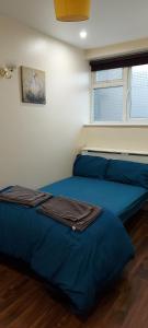 1 dormitorio con 2 camas azules y ventana en Romford Lodge en Romford