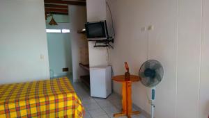 Habitación con cama, TV y ventilador. en Amotape Home, en Cruz de Pizarro