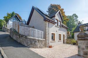 a white house with a stone wall and a fence at Wallace's Rest in Stirling