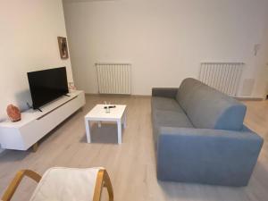 sala de estar con sofá azul y TV en appartamento Alpi Orobie, en Morbegno