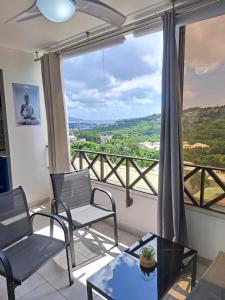 een woonkamer met stoelen en een tafel en een groot raam bij Super appartement T3 proche de tout sans vis-à-vis in Fort-de-France