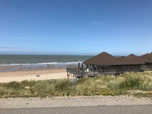 een gebouw op een strand met de oceaan bij Zeewind en Zonneschijn in Oostburg