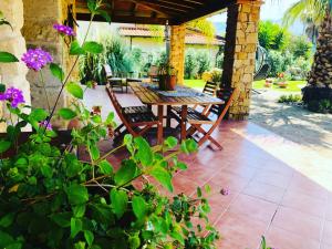 a wooden table and chairs on a patio with purple flowers at Villa Oleandra Relais in Partinico