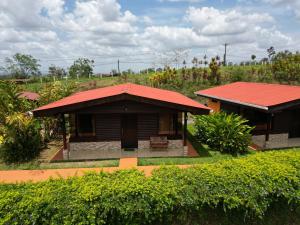 una pequeña casa con techo rojo junto a un campo en Cabañas Sueños del Arenal, en Fortuna