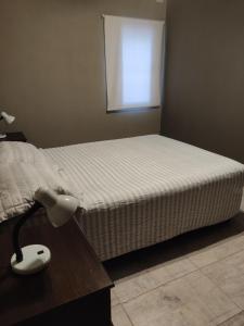 a bedroom with a bed and a lamp on a table at Apart Trelew 1 in Trelew
