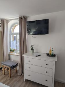 a bedroom with a dresser with a tv on the wall at Ferienwohnung Kaffestübchen 
