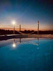 a swimming pool with a volleyball net in the sunset at La Bruyère - B & B - in Tréban