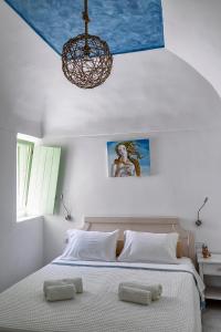 una camera da letto con un grande letto e un lampadario a braccio di Mythos Traditional Stonehouse a Kamari