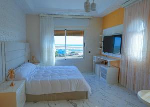 ein weißes Schlafzimmer mit einem großen Bett und einem TV in der Unterkunft Villa vue sur mer avec piscine in Tangier