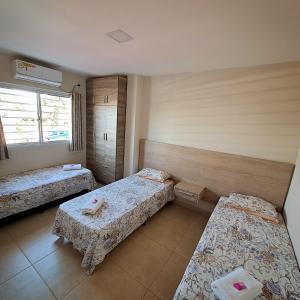 a room with three beds and a window at Taroba Apart in Puerto Iguazú