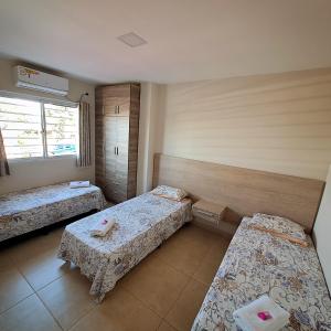 Habitación con 3 camas y ventana en Taroba Apart en Puerto Iguazú