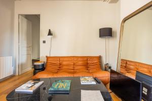 - un canapé orange dans le salon avec une table dans l'établissement Bail Mobilite Luxe Le Marais, à Paris