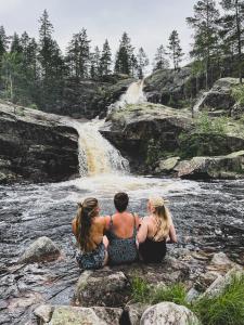 un gruppo di tre persone sedute sulle rocce vicino a una cascata di Bolkesjø Gaard a Notodden