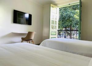 Hotel Casa Quintana في Aguadas: غرفة نوم بسريرين وكرسي ونافذة