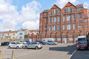 a parking lot with cars parked in front of a large brick building at Let's go sea in Swansea