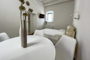 a white room with a white table with a vase on it at B&B Dimora Orrù in Càbras