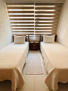 two beds in a small room with windows at Apartamento Delux Morros-Tolusa in Cartagena de Indias