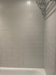 a bathroom with a shower with a white tile wall at Rendezvous in Romford