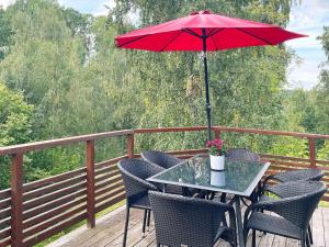 una mesa con una sombrilla roja en una cubierta en 6 person holiday home in GR NNA, en Gränna