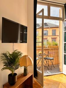 een woonkamer met een flatscreen-tv aan de muur bij Aux Arcades Mulhouse Hyper Centre in Mulhouse