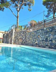 a swimming pool in front of a stone wall at Dolce Far Niente in Alassio