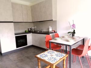 a kitchen with a table and red chairs in a room at Dolce Far Niente in Alassio