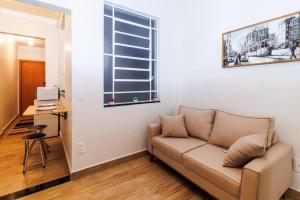 a living room with a couch and a desk with a laptop at Studio 112 Campinas SP in Campinas