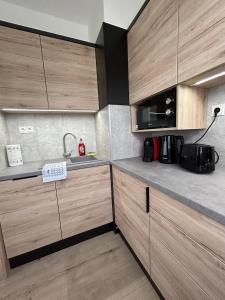 una cocina con armarios de madera y fregadero en Dani Wellness Apartman en Zalakaros