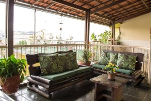un porche cubierto con 2 sillas y una mesa en Recanto da Sol en Belo Horizonte