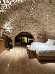 a bedroom with a bed in a stone wall at Hagafen Boutique Suites in Zikhron Ya‘aqov