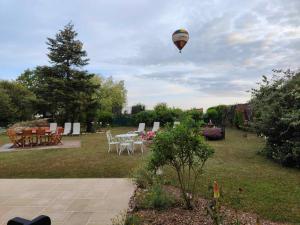 a hot air balloon flying in the sky over a yard at La Maison Genevier - Chambre Doréline in Montreuil-en-Touraine