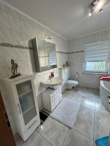 a white bathroom with a sink and a toilet at Ferienwohnung auf dem Fels in Kall