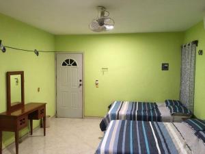 a bedroom with two beds and a desk and a door at Casa Caribe in Bacalar